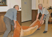 Zwei Männern wickeln den toten Zwillingsbruder in einen Teppich ein und tragen ihn