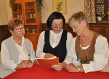 Drei Frauen sitzen am Tisch und gehen Zahlen durch